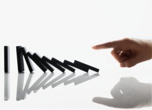 Businessman Touching Domino Pieces Arranged in a Line --- Image by © Royalty-Free/Corbis